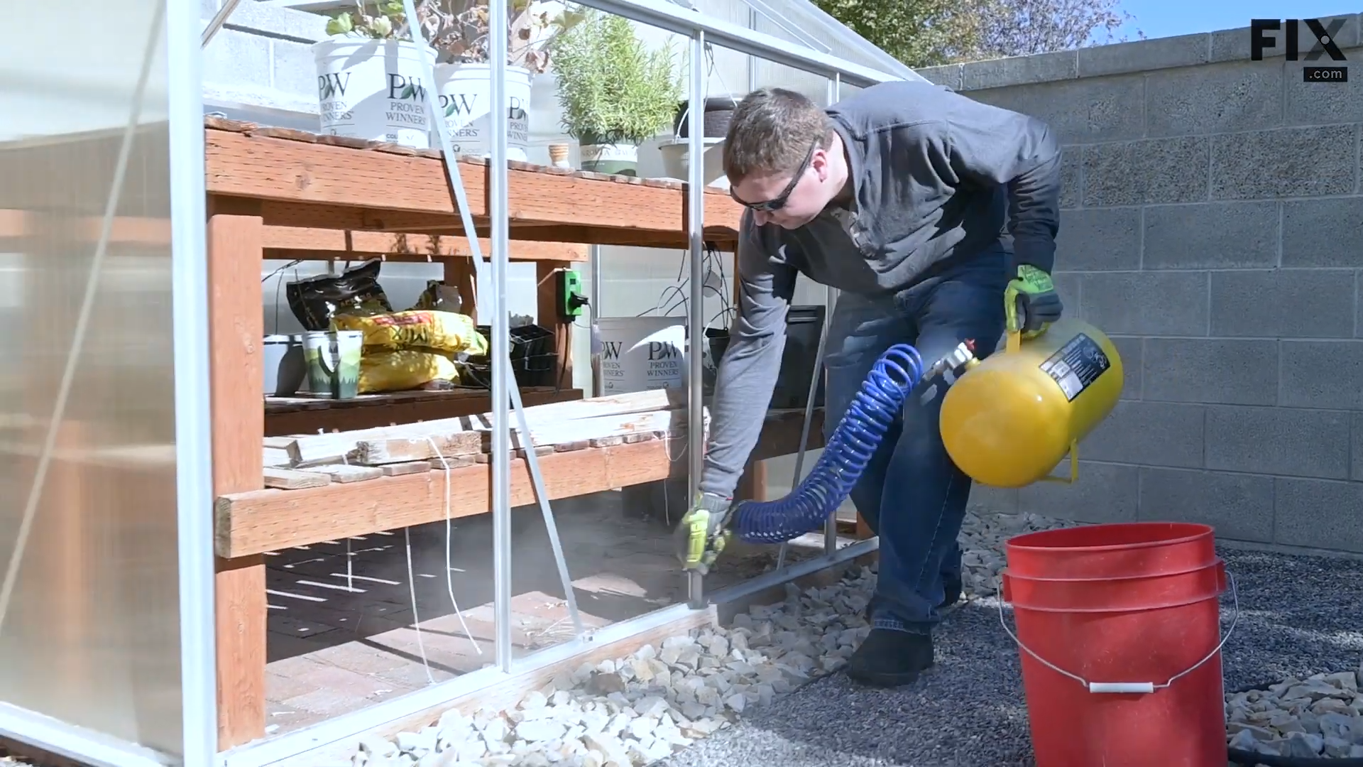 Expert technician blowing away dirt from a greenhouse's frame with compressed air