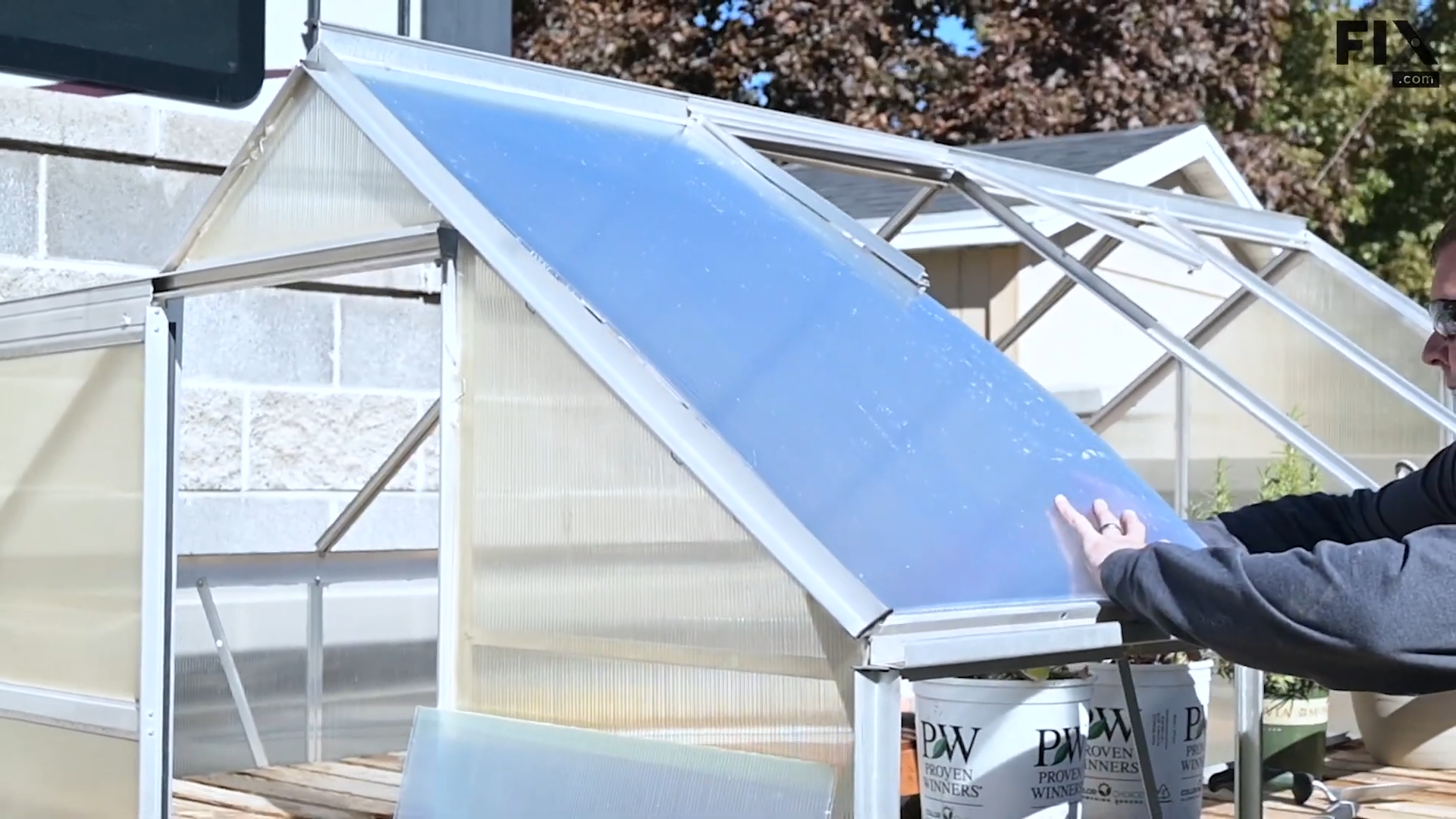 Expert technician installing a roof panel of a greenhouse by slotting it into its frame