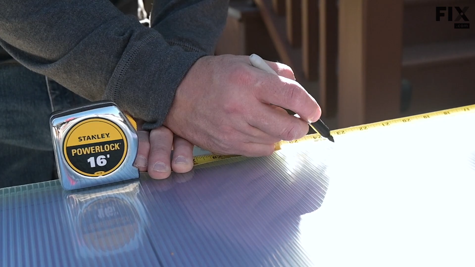 Expert technician using a measuring tape and a marker to measure the size of a greenhouse panel and marking it on a sheet of double-wall polycarbonate