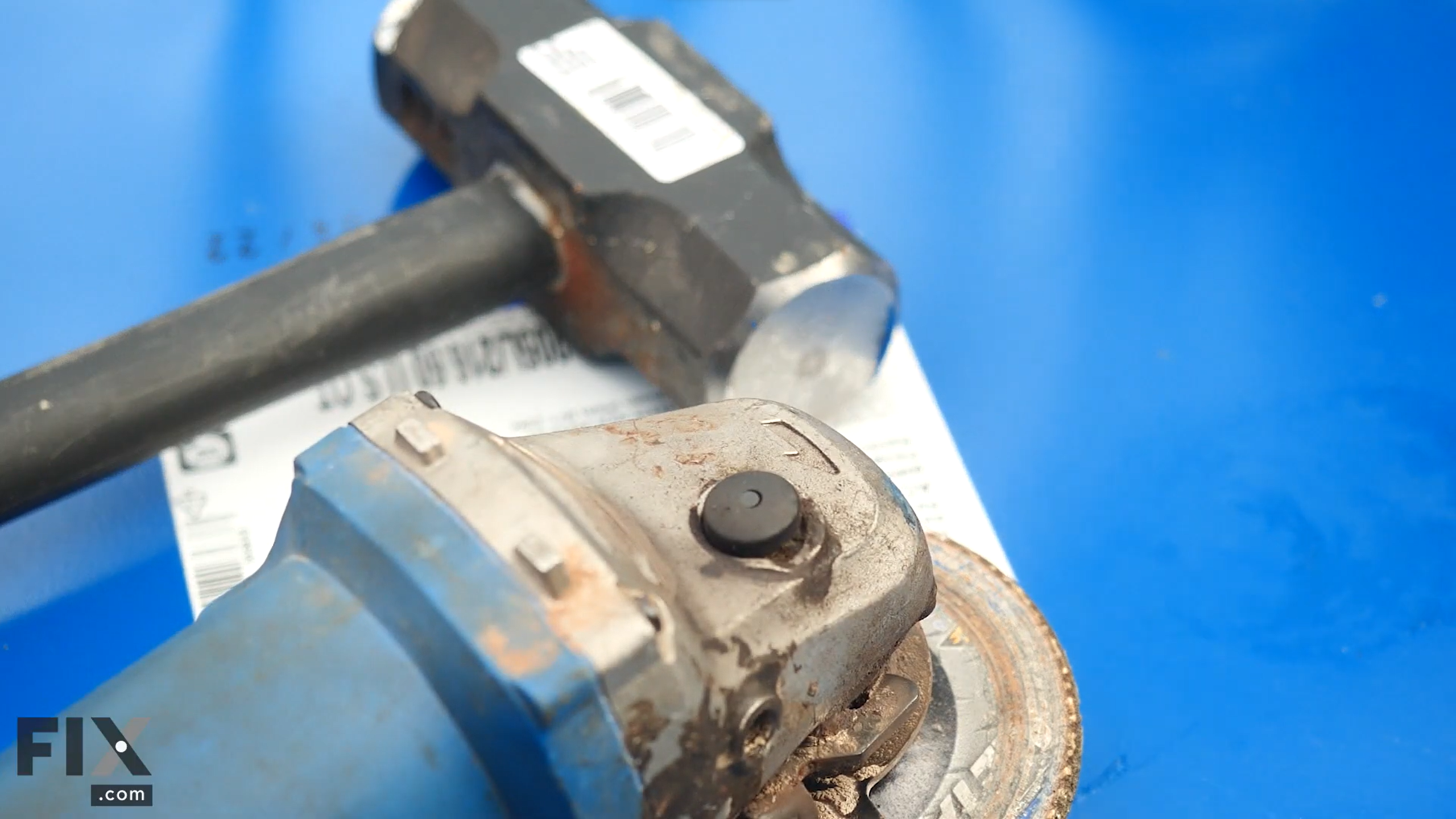 Grinder and hammer sitting on lid of blue metal surface.