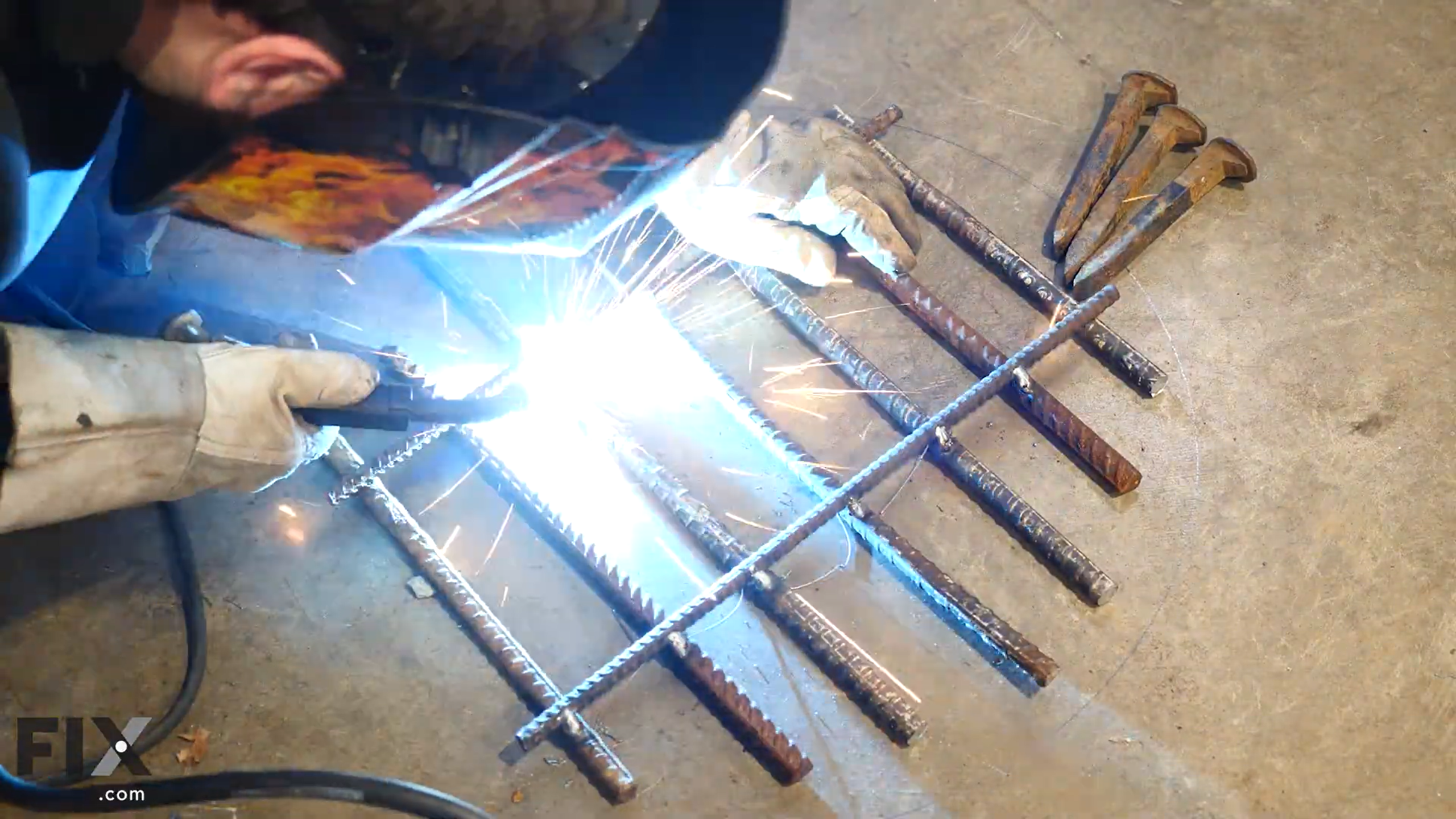Welder creating sparks welding grate together with metal.