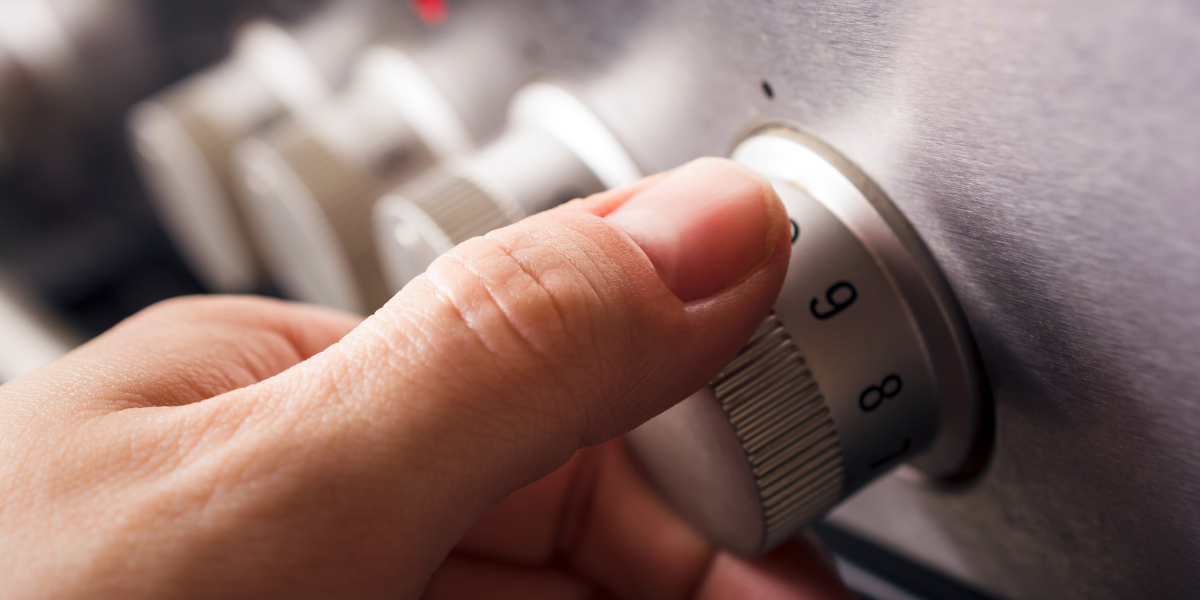 Hand gripping a numbered control knob on stainless steel range appliance
