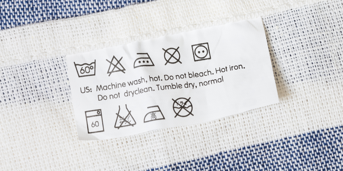 Blue and white cloth accompanied by a care label showing that the fabric can be machine washed, hot ironed, and tumble dried.