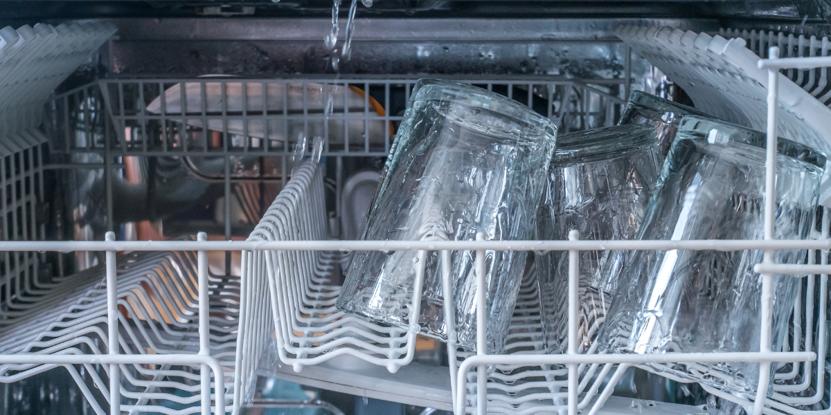 Drinking glasses placed on a rack inside a dishwasher during a wash cycle